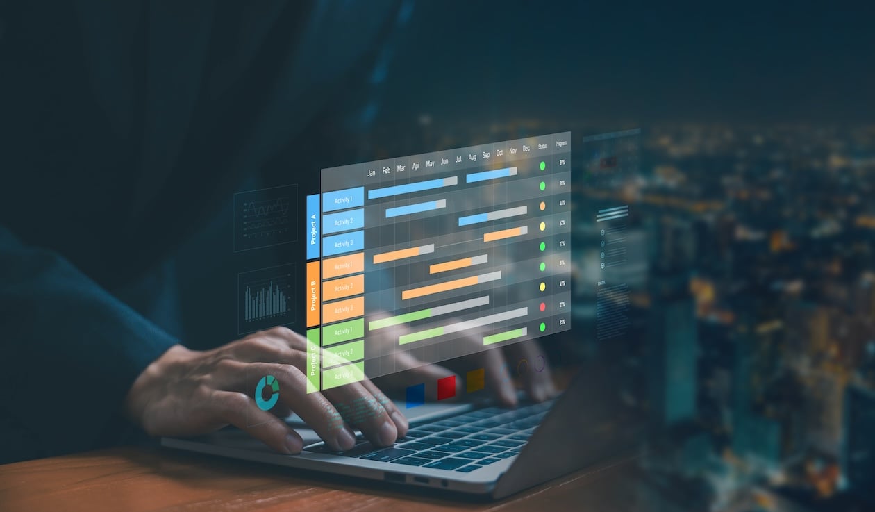 Businessman using a laptop with a digital project management dashboard showing scheduling timelines and workflow planning