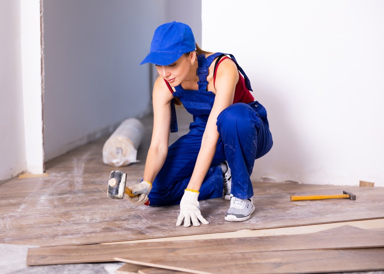 Flooring installer installing laminate flooring in an apartment during a residential job