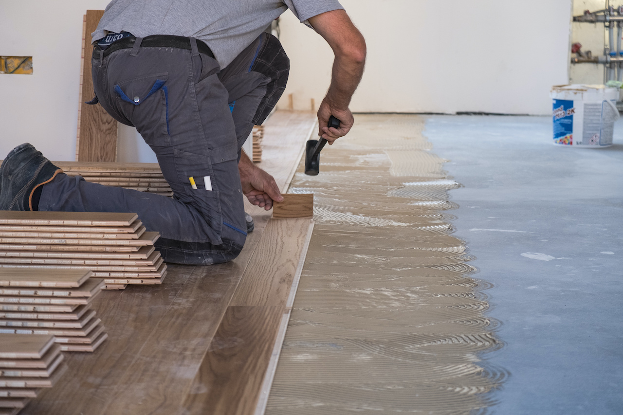 Flooring intaller using applied adhesive during installation.