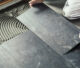 Worker installing dark grey ceramic tiles.