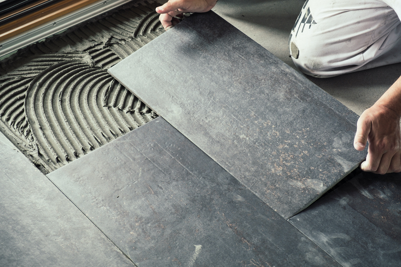 Worker installing dark grey ceramic tiles.