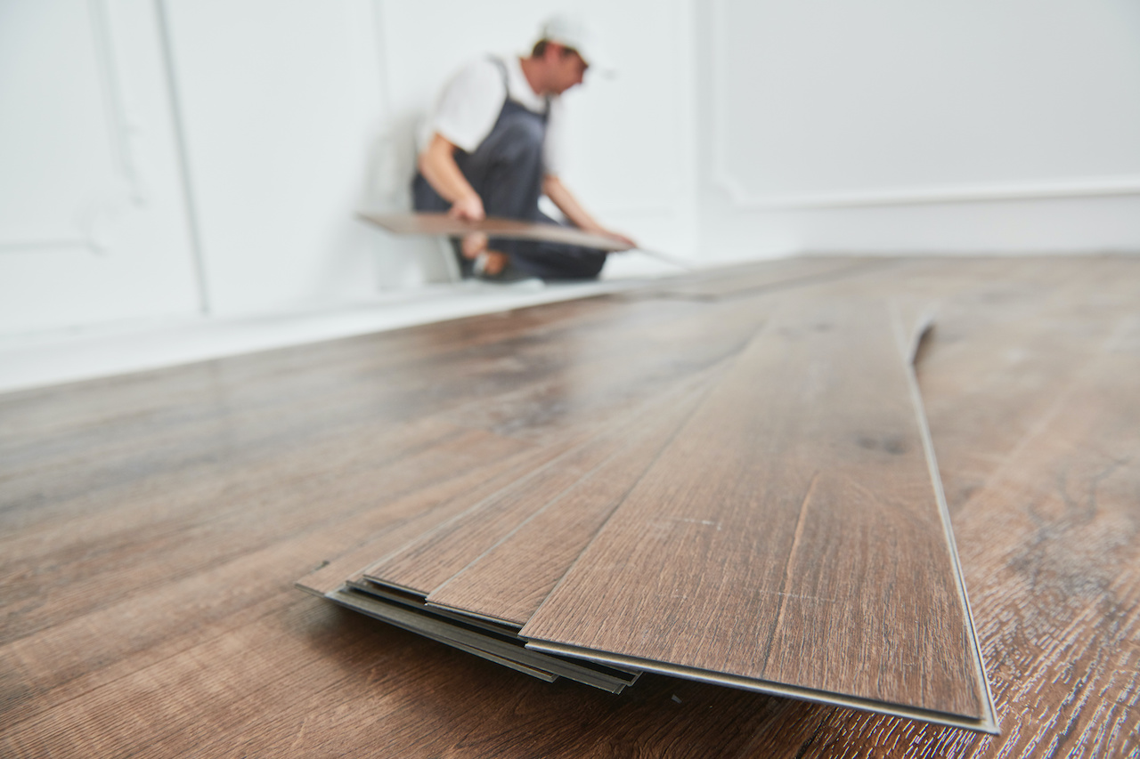 Working laying down laminate flooring during installation.