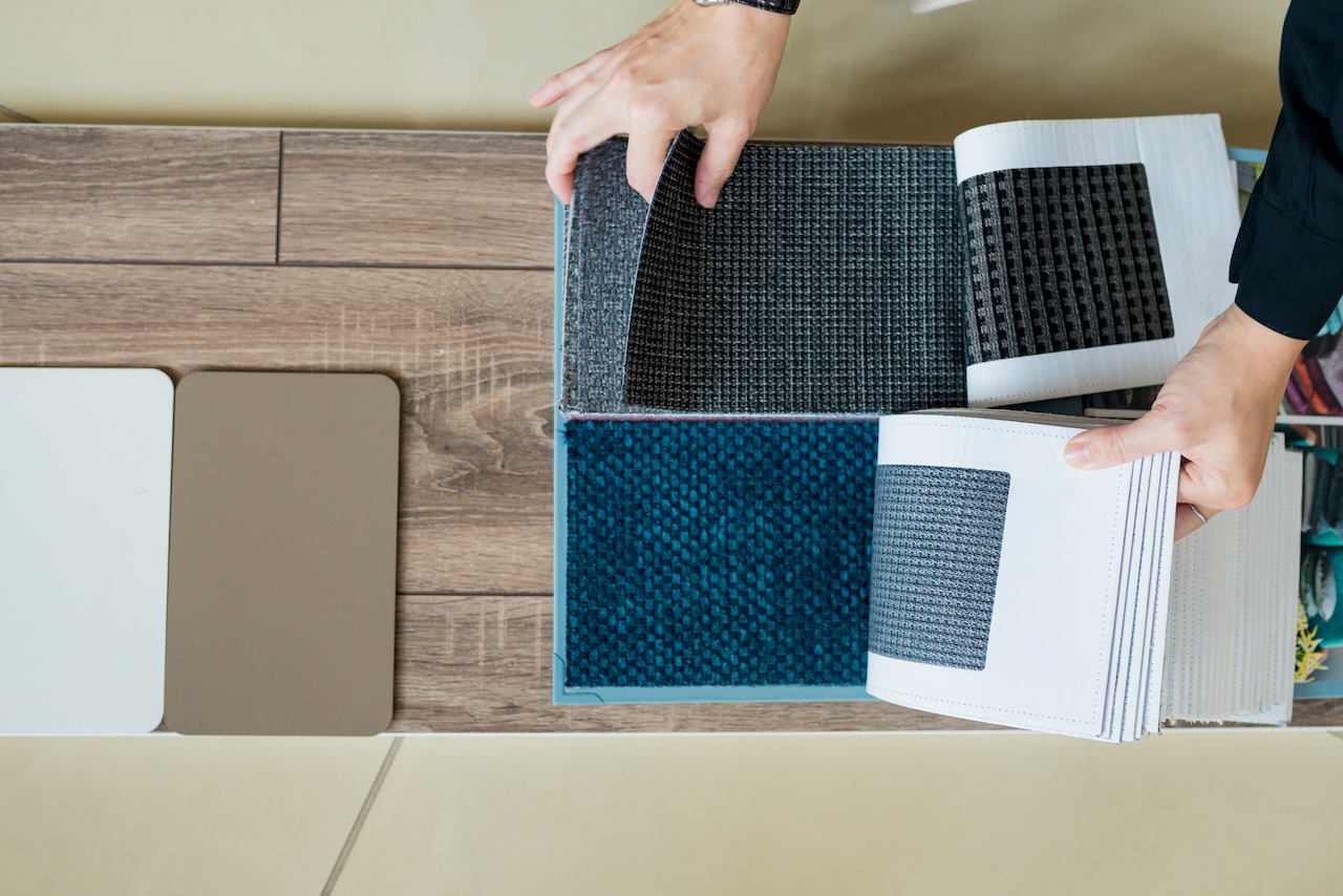 Interior designer selecting flooring materials and matching wall colors with parquet samples during a home renovation project.