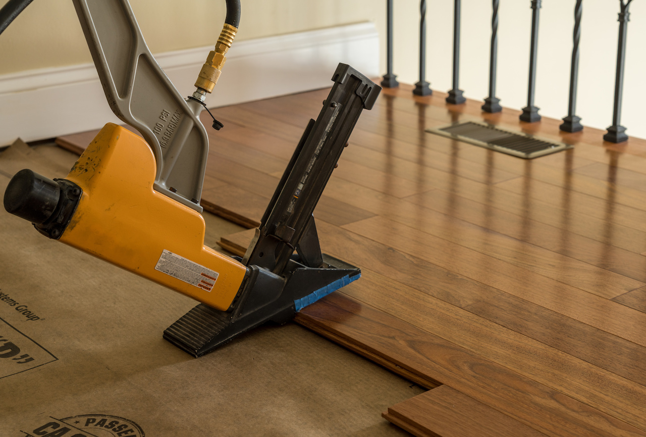 Nailing gun ready to staple sections of hardwood flooring