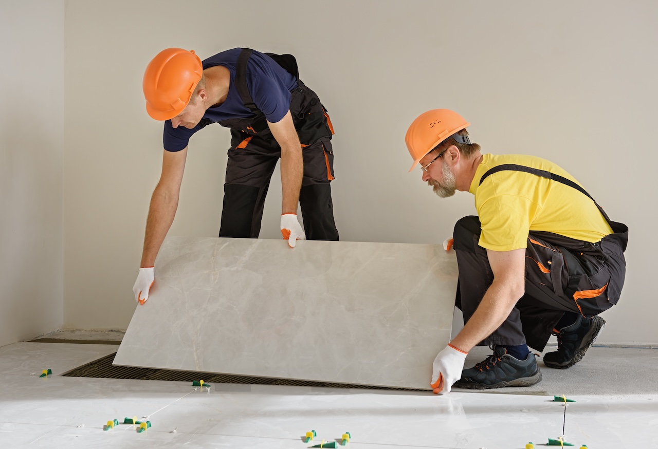 Two workers installing large ceramic tile