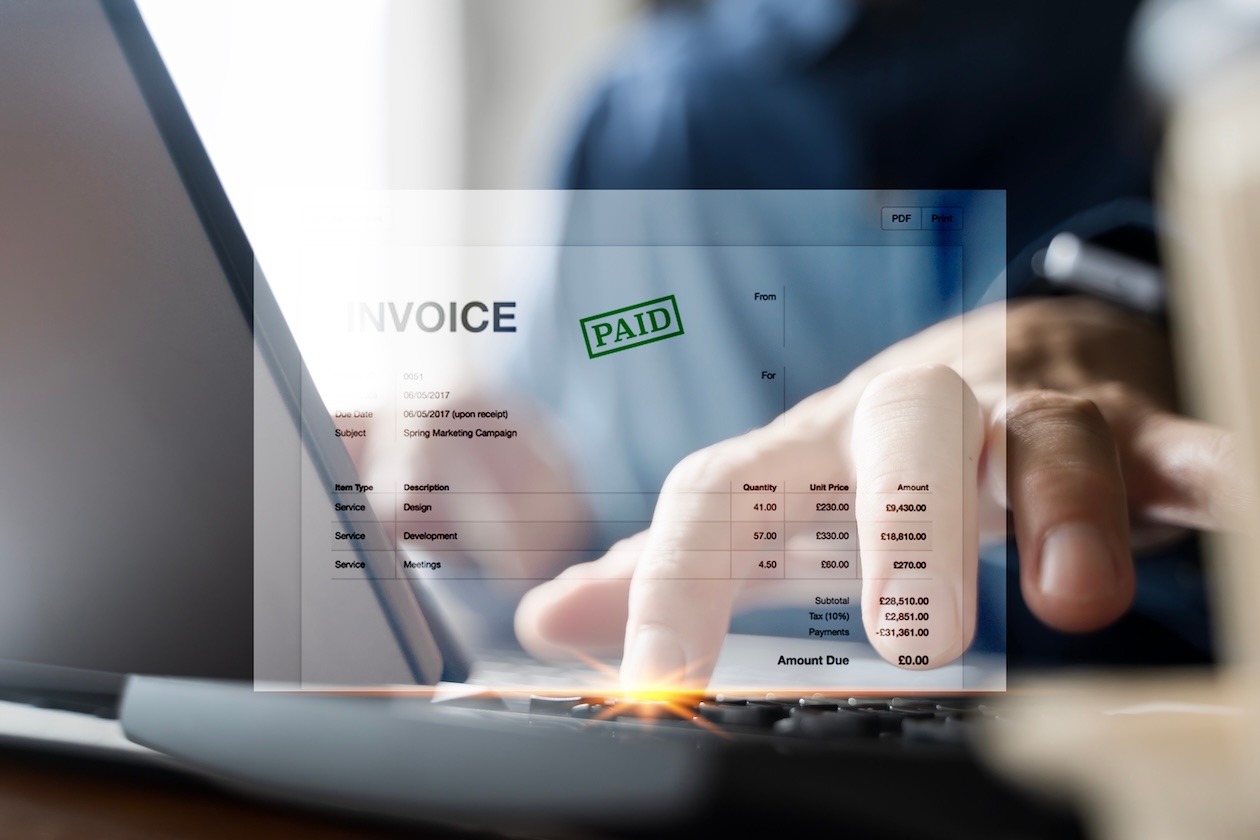 Businessman using laptop to confirm online invoice payment.