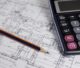 Pencil and calculator resting on a house floor plan.