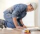 Flooring professional installing a floor with hardhat on.